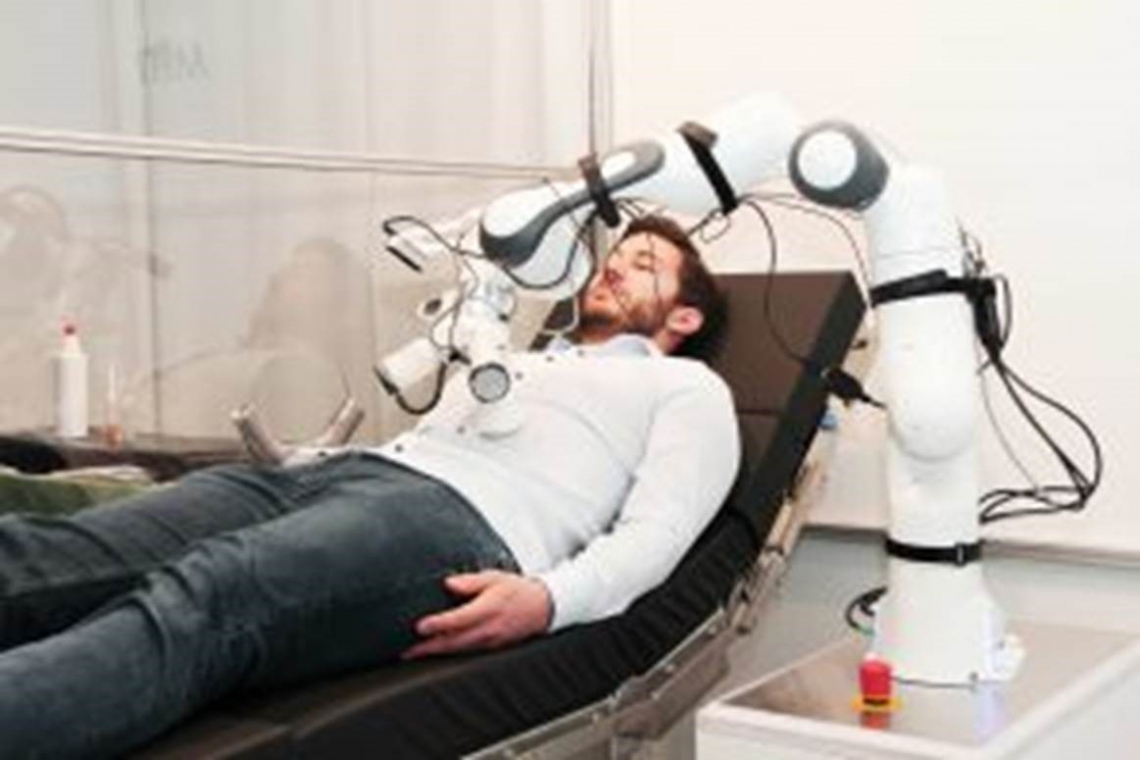 Ein Roboterarm in der Kabine beim Abtasten des Bauchs des Testpatienten 
